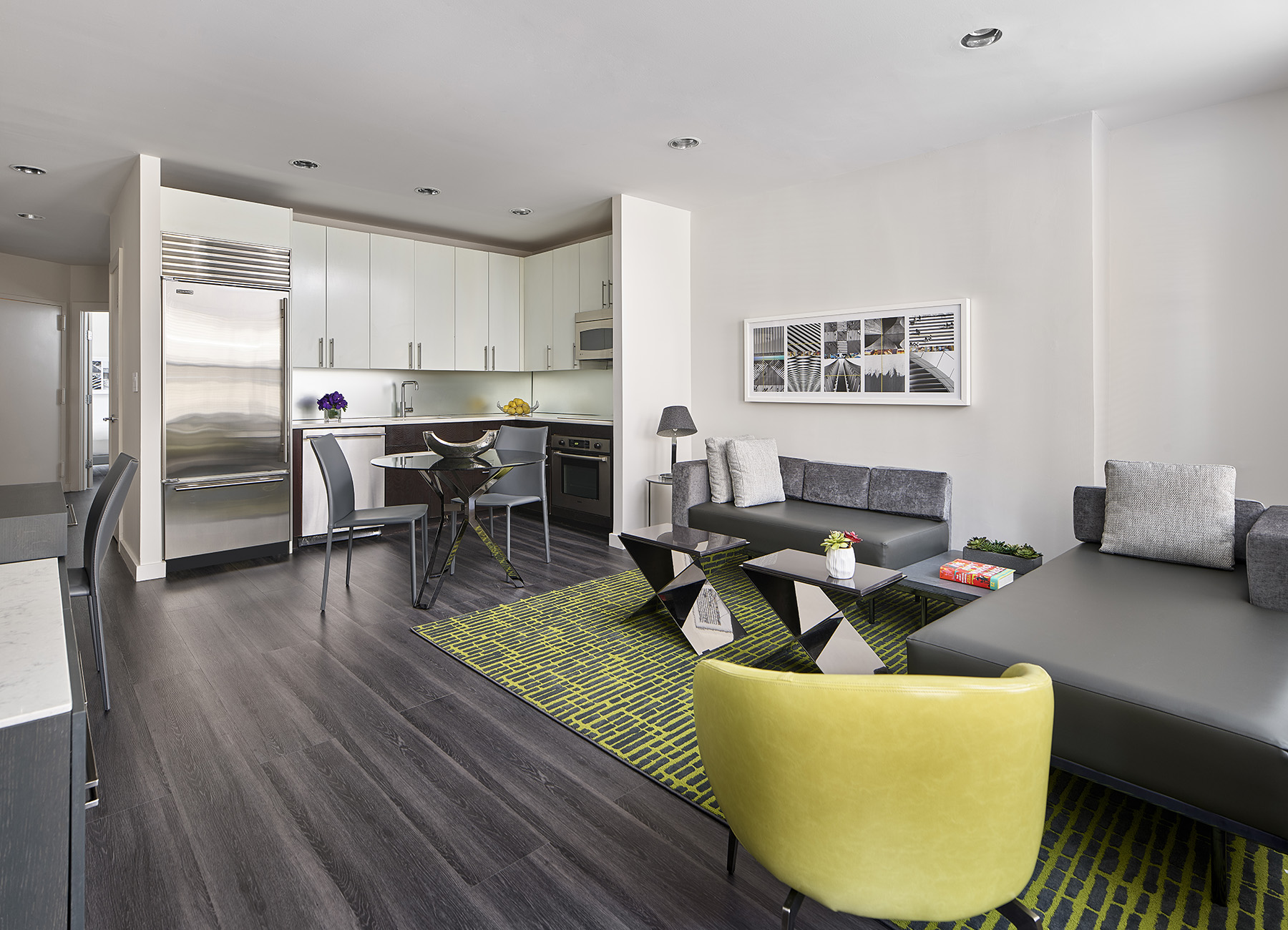 AKA Times Square premium suite living room and kitchen with green rug and modern yellow chair