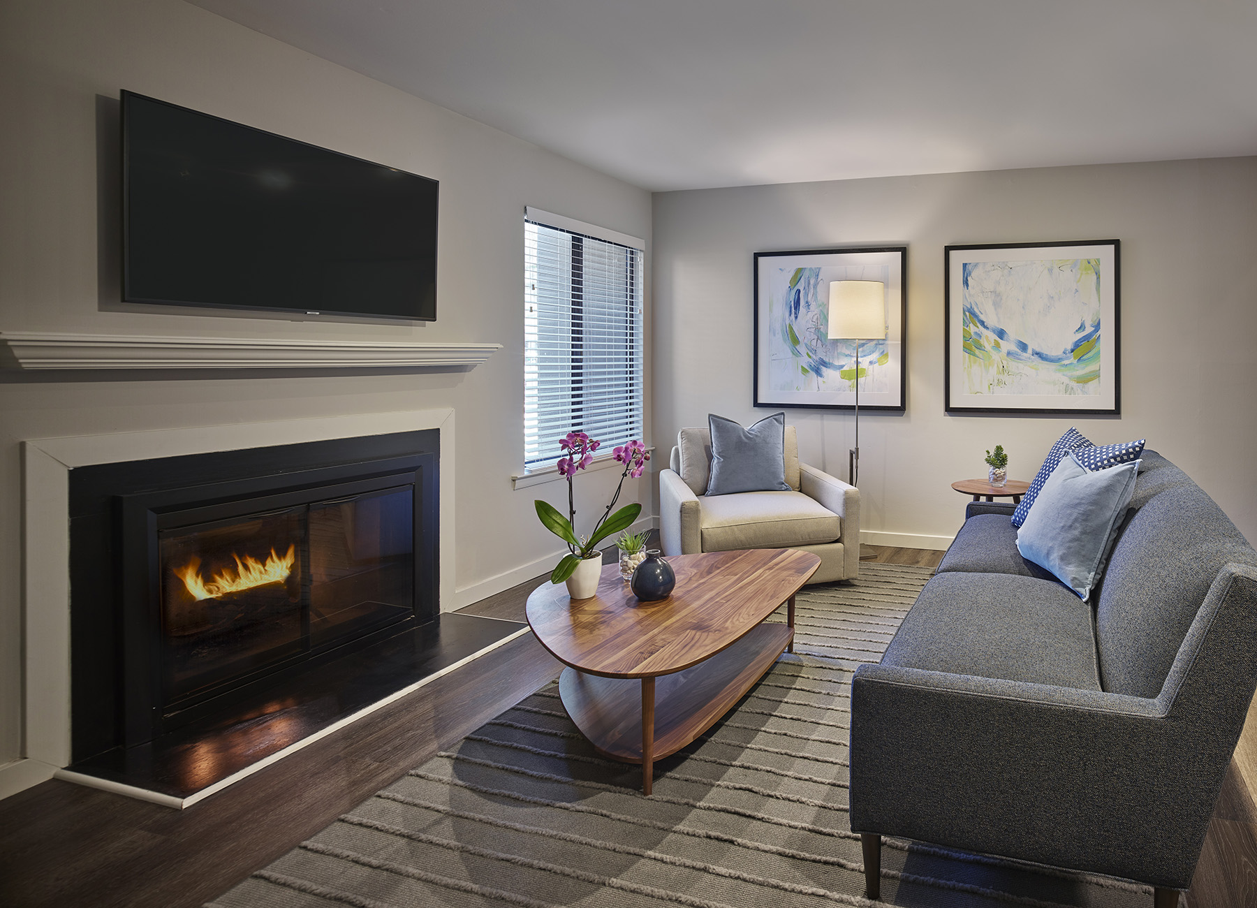 AVE Blue Bell Villas apartment living room with blue cushions on gray couch and a wood burning fireplace