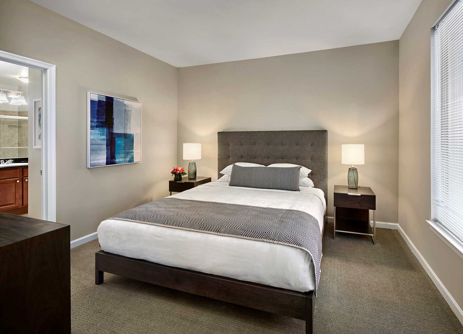 AVE Union furnished apartment bedroom with king bed, en-suite bathroom, and sophisticated artwork