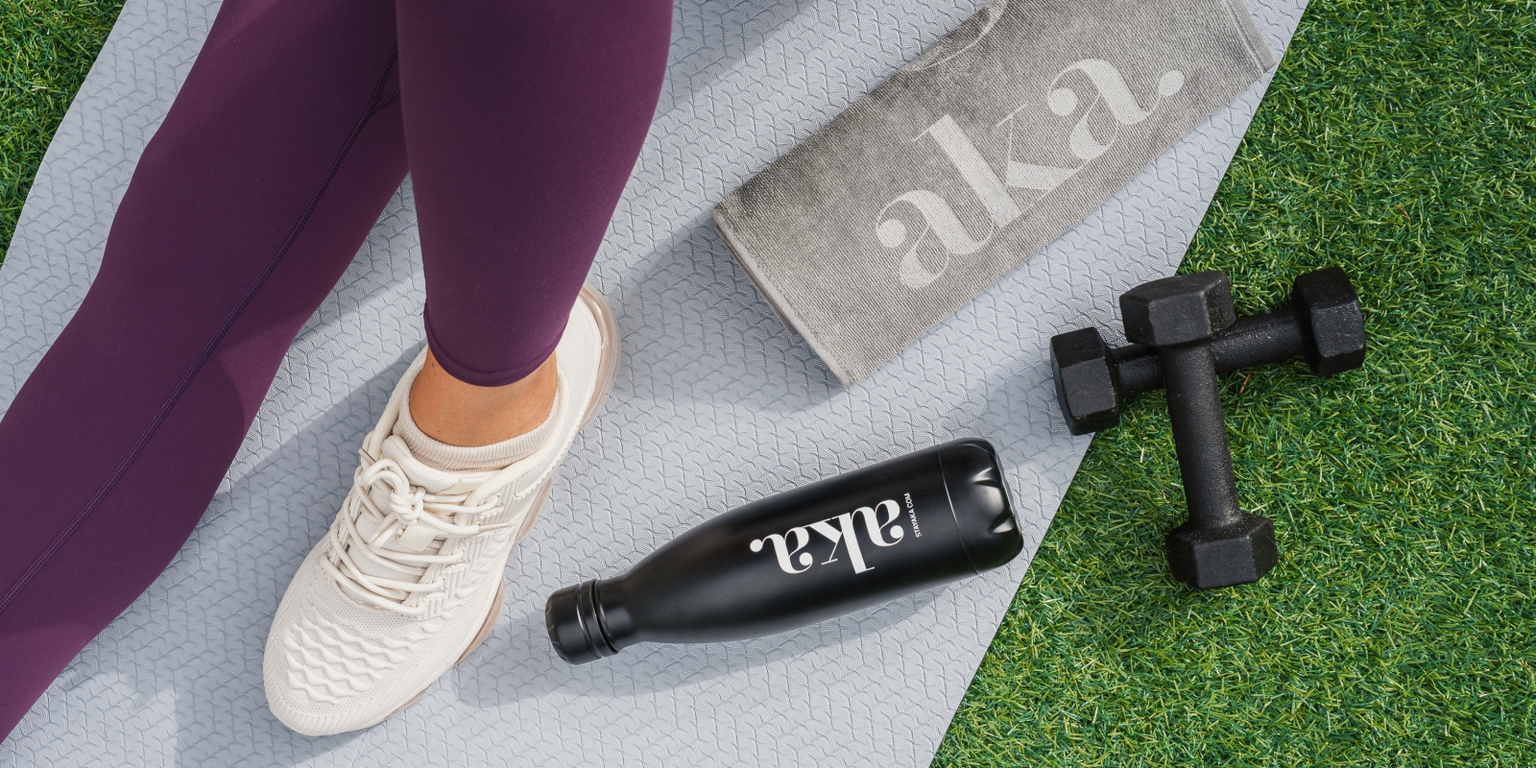 a close up shot of woman's foot in sneaker with aka water bottle and dumbbells next to it 