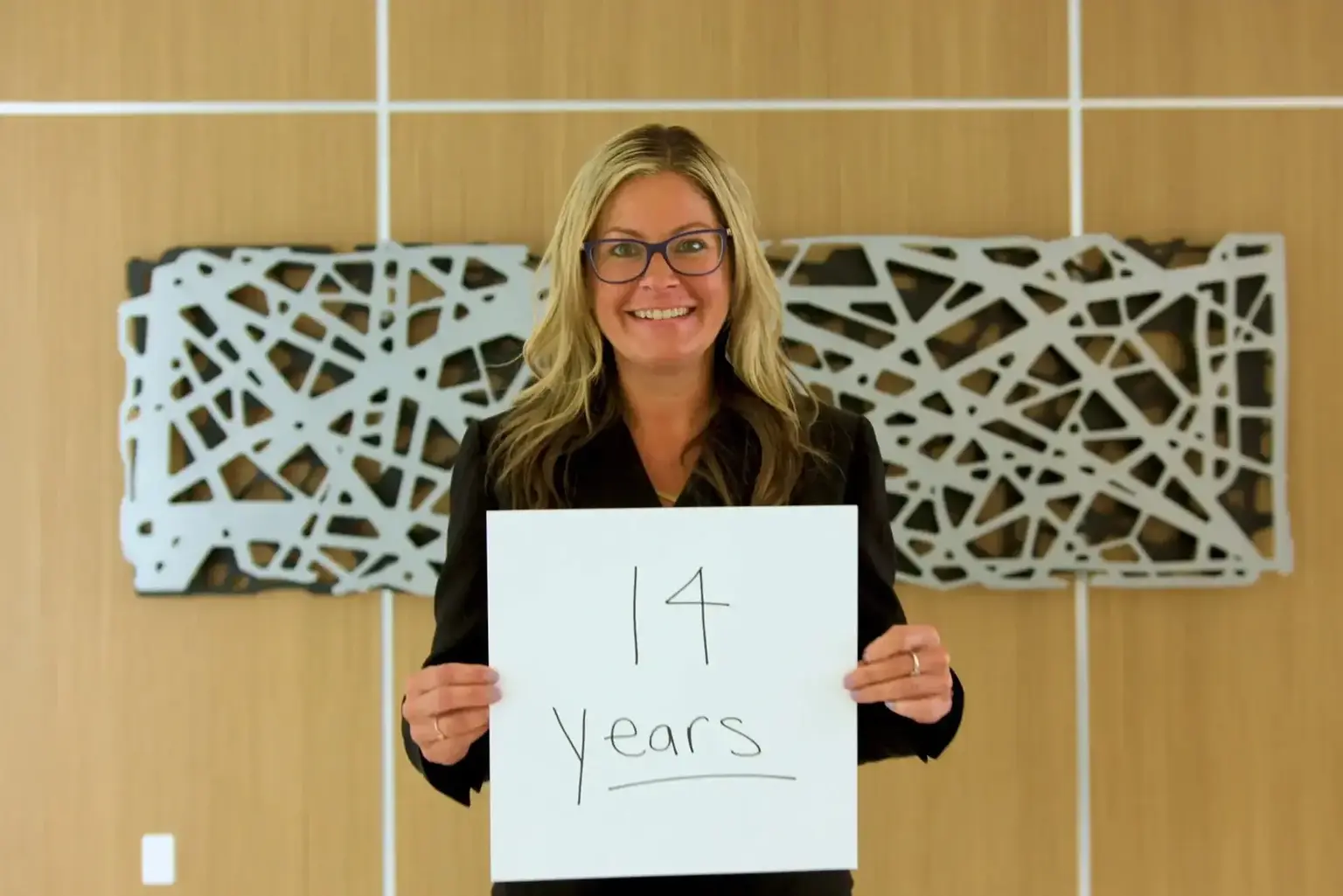 AVE Team Member holding a sign with 14 years written on it