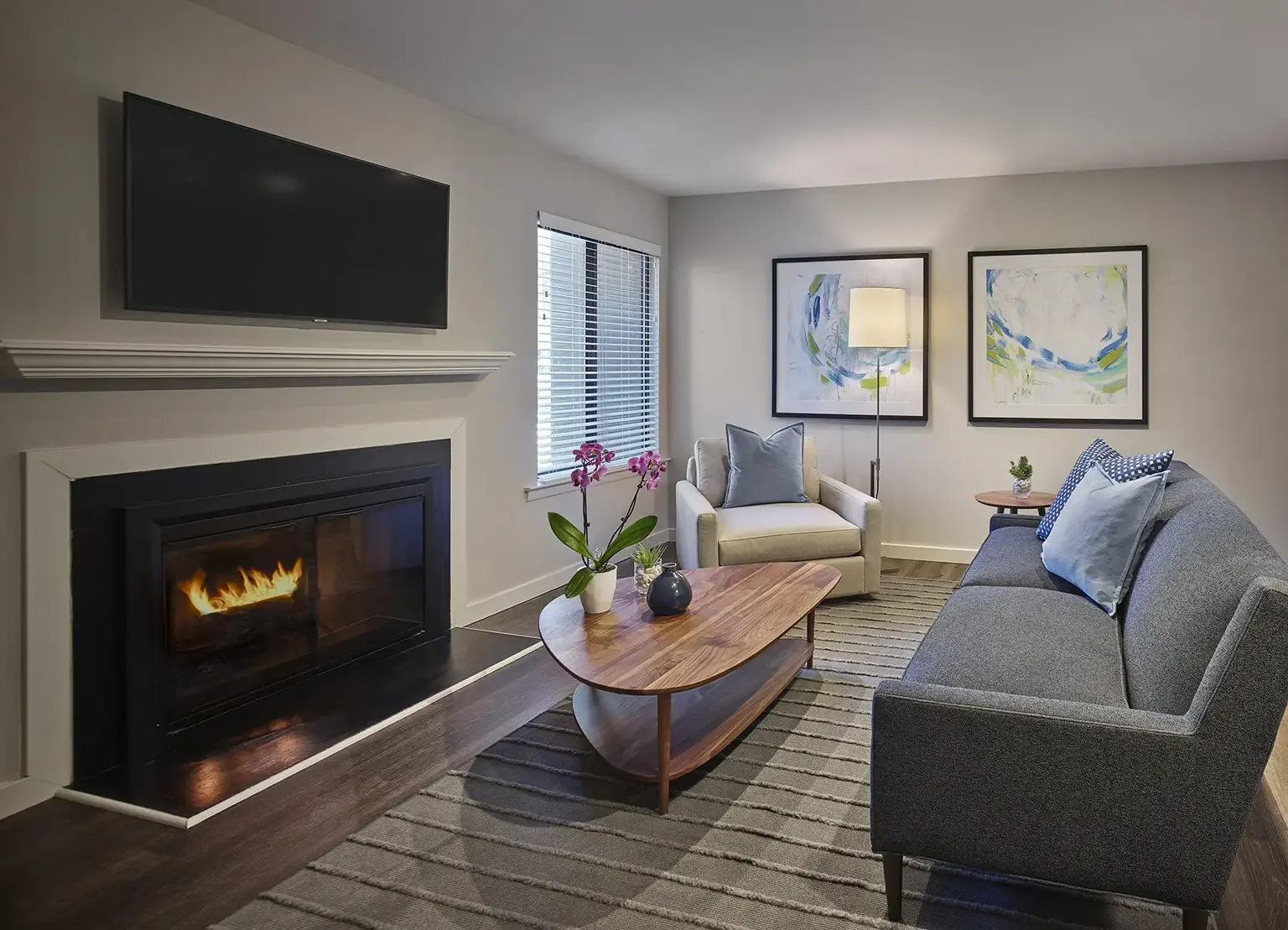 AVE Blue Bell Villas apartment living room with blue cushions on gray couch and a wood burning fireplace