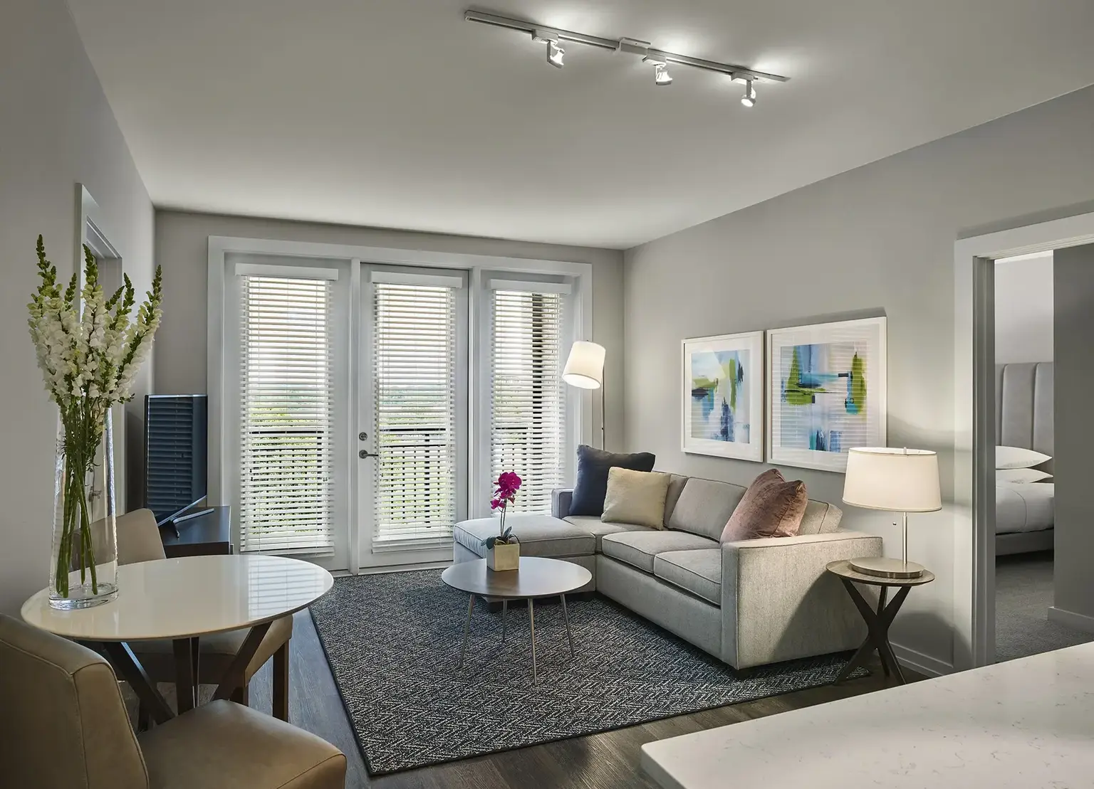 AVE King of Prussia furnished apartment living room with cream couch on a gray rug facing television bank.