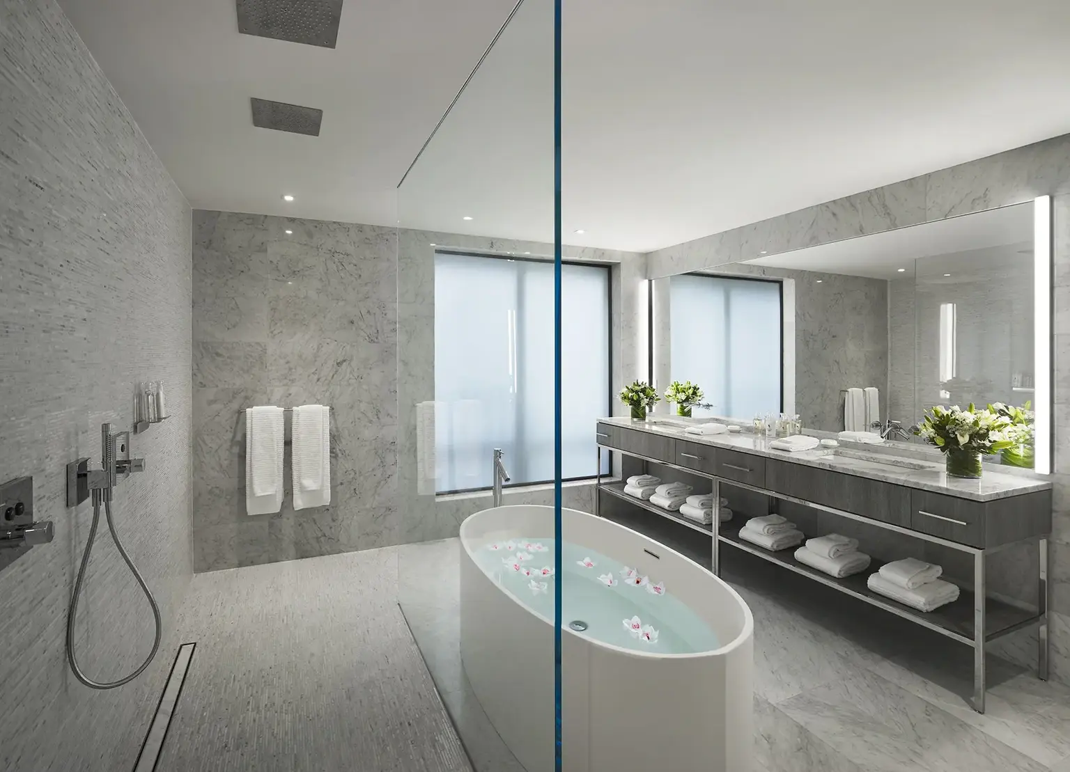 AKA Times Square apartment bathroom with marble finishings, standing tub, shower, and large vanity