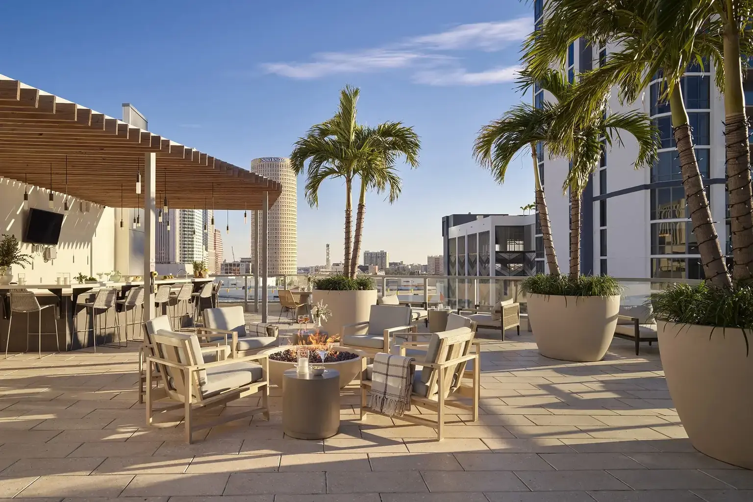 AVE Tampa Riverwalk Outdoor Terrace with a view of the water surrounded by palm trees and with fireplace on