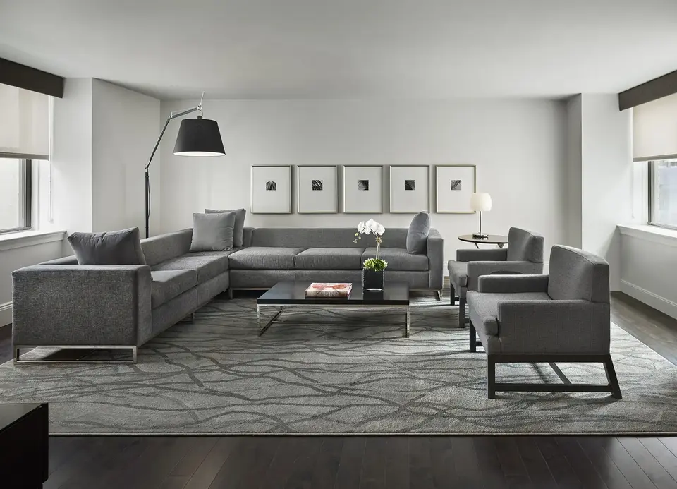 AKA Central Park furnished apartment living room with gray couch and chairs on floor rug