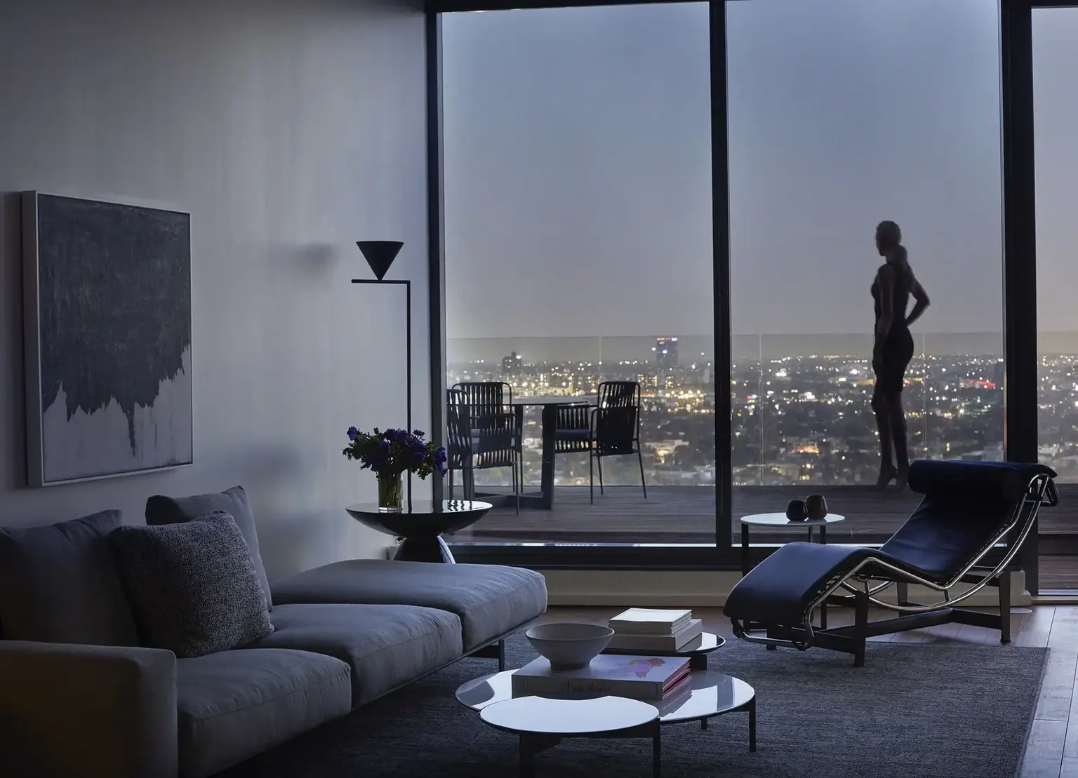 AKA West Hollywood apartment view of city at dusk with silhouette of woman standing on balcony 