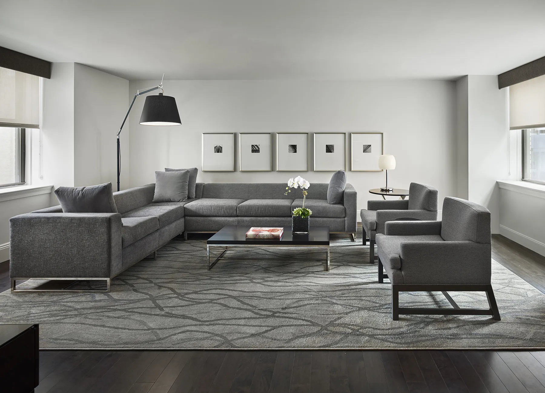 AKA Central Park furnished apartment living room with gray couch and chairs on floor rug