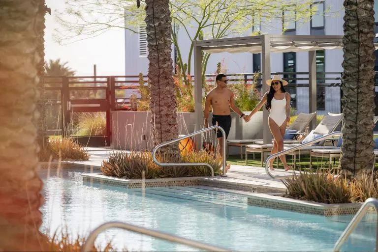 A couple walking by the pool in AVE Phoenix SKY at sunset