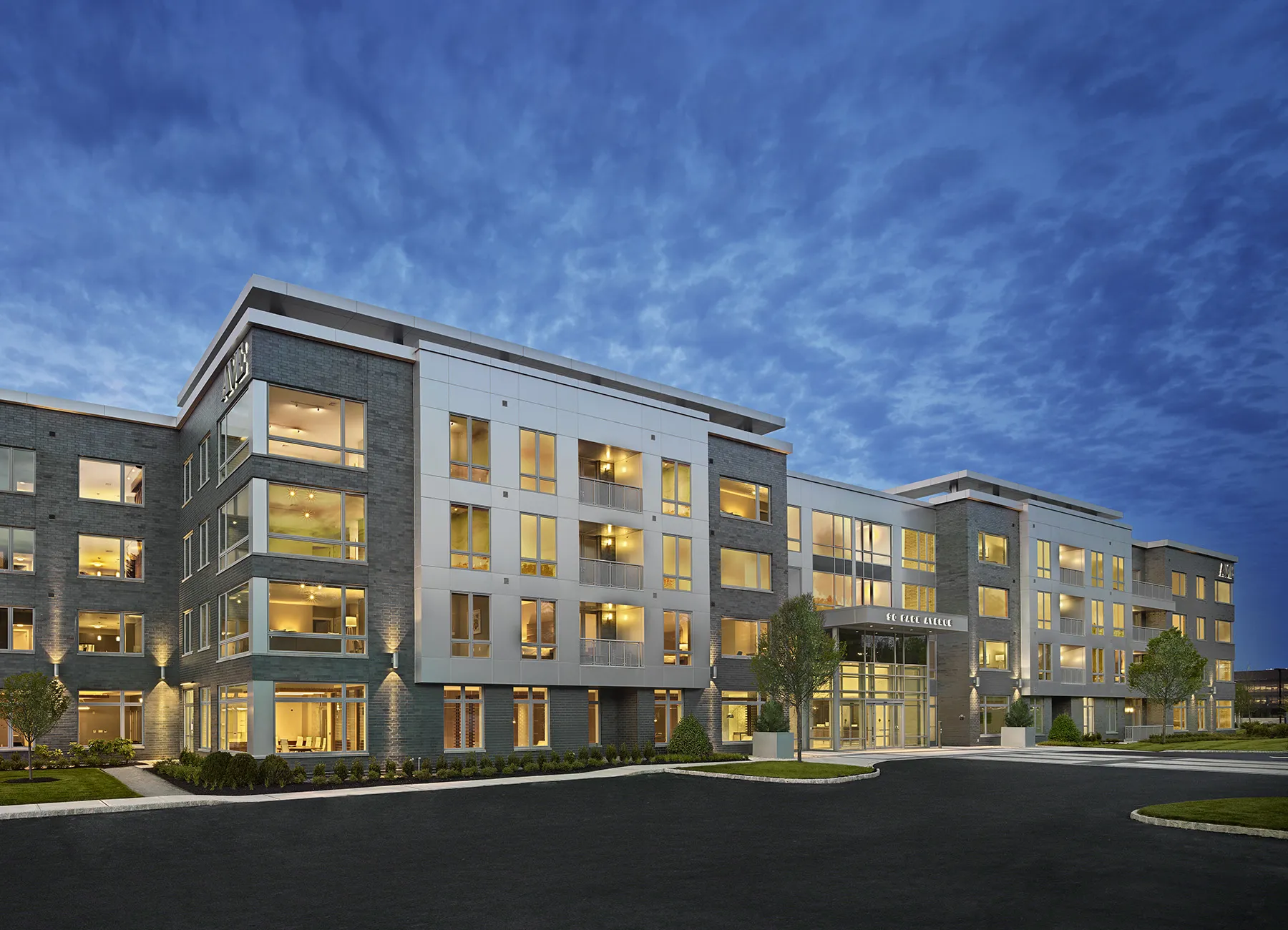 Four story apartment building at night with windows illuminated