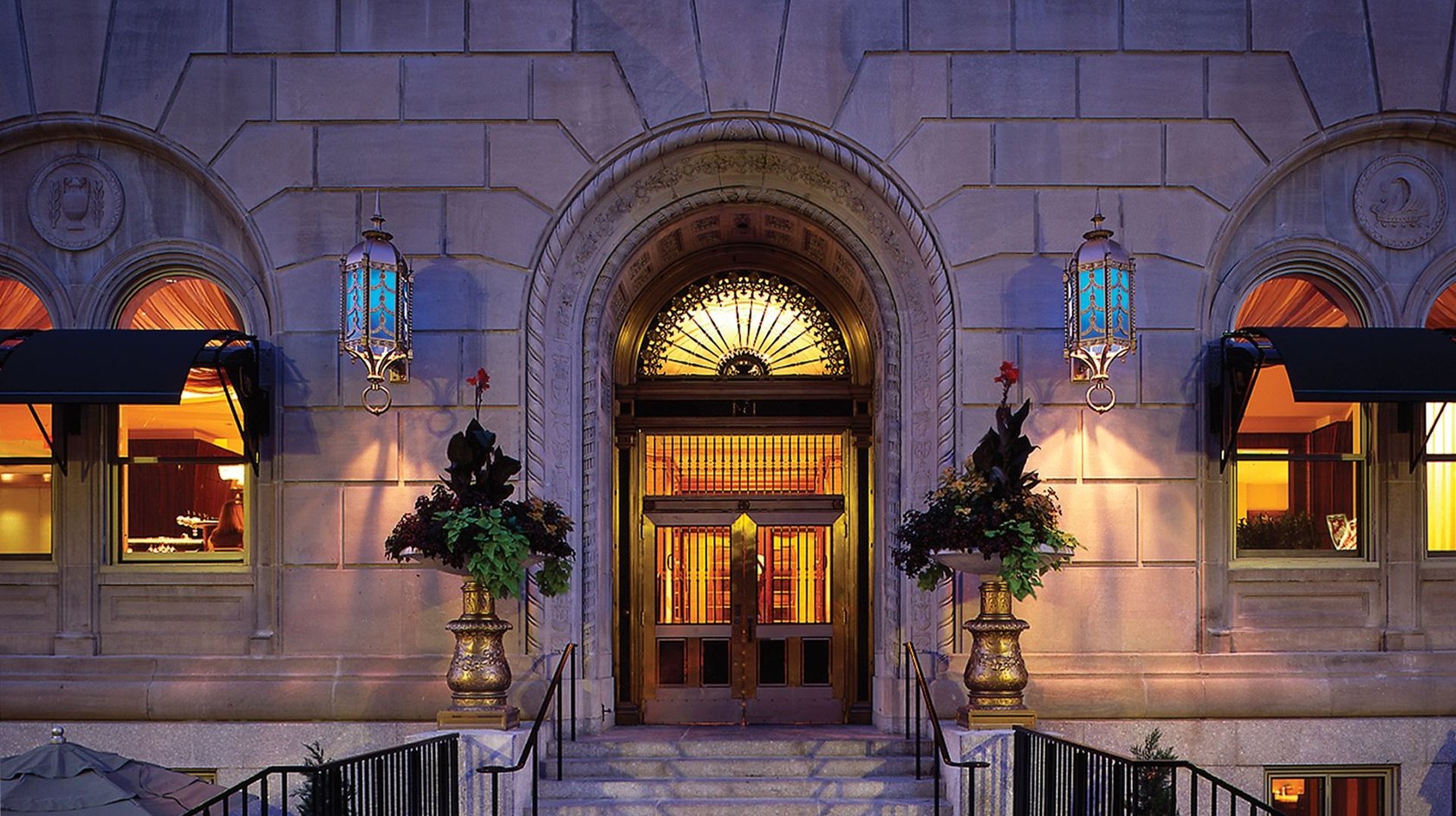 Entrance to Hotel AKA Back Bay apartment building in Boston with vintage glass doors and two vases 