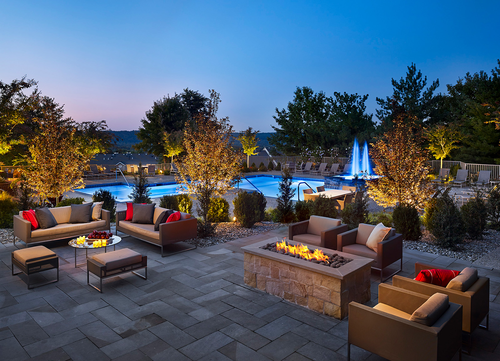 Firepit and lounge chairs in front of pool at night