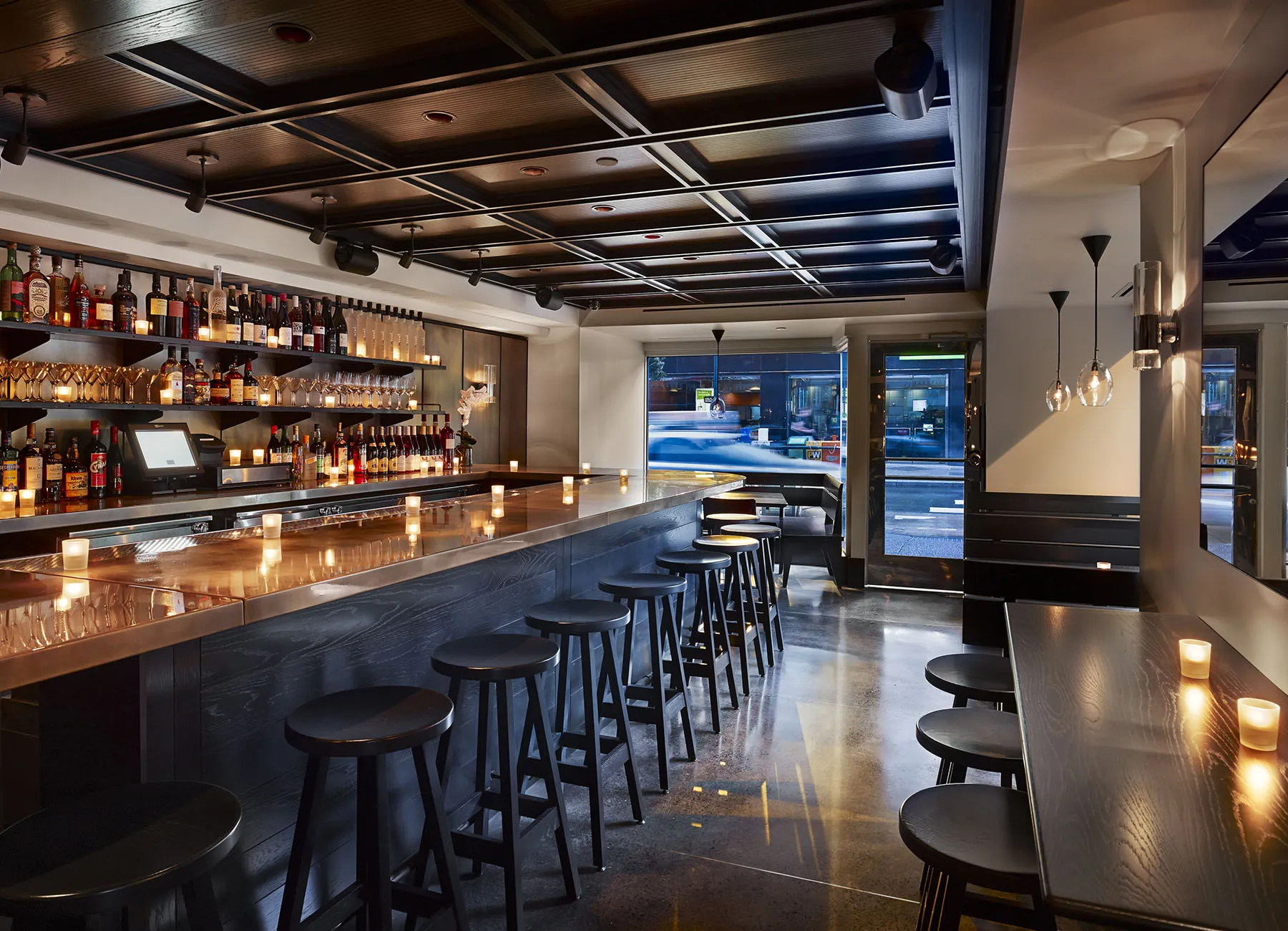 AKA Rittenhouse Square a.bar interior view with candles along the bar, and booth tables