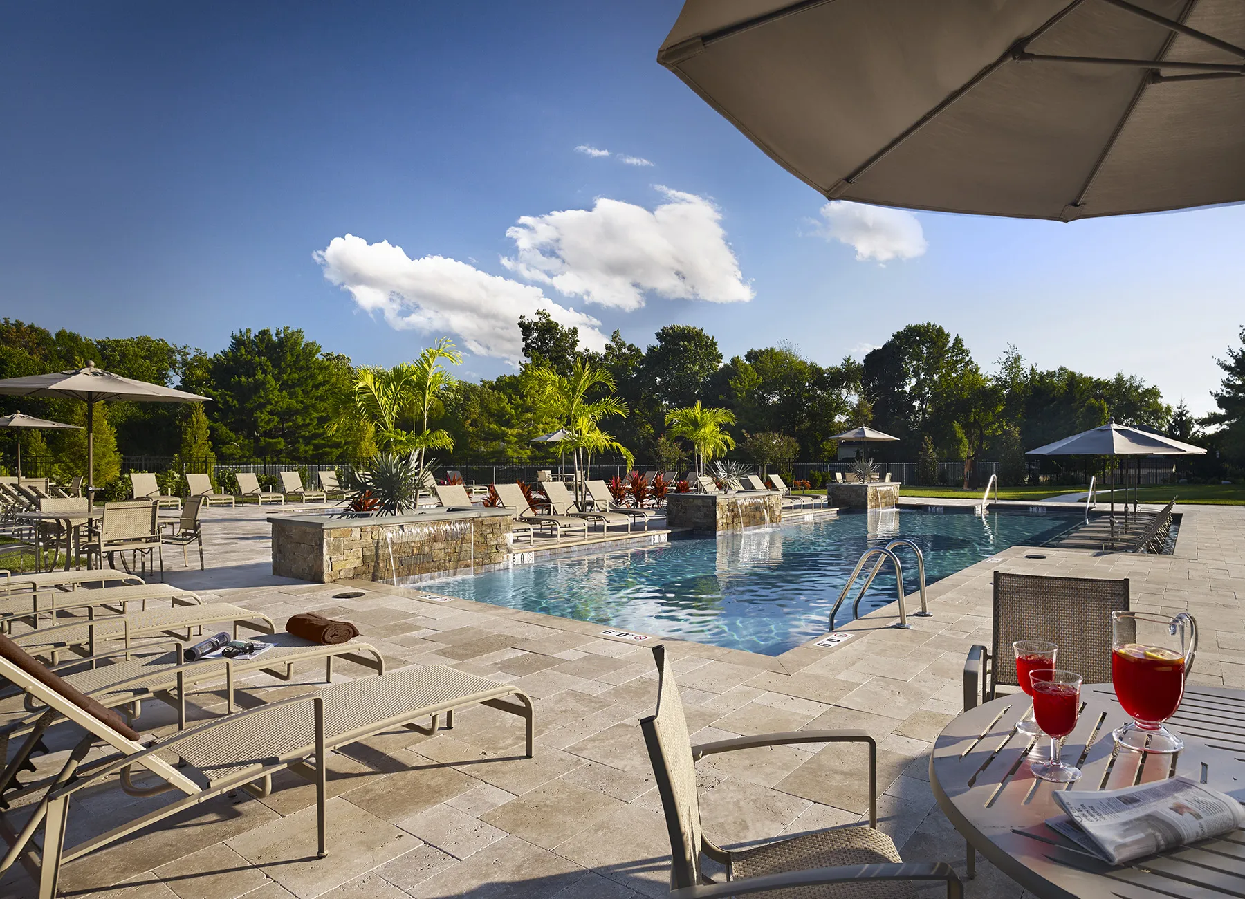 AVE Blue Bell Villas apartment community in-ground pool with lounge chairs and tables around in the daytime