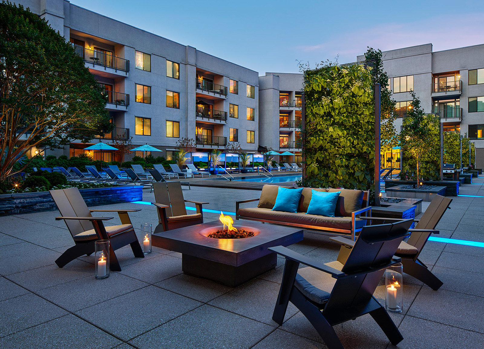 AVE Clifton apartment building at sundown with lounge chairs around firepit and pool in the background
