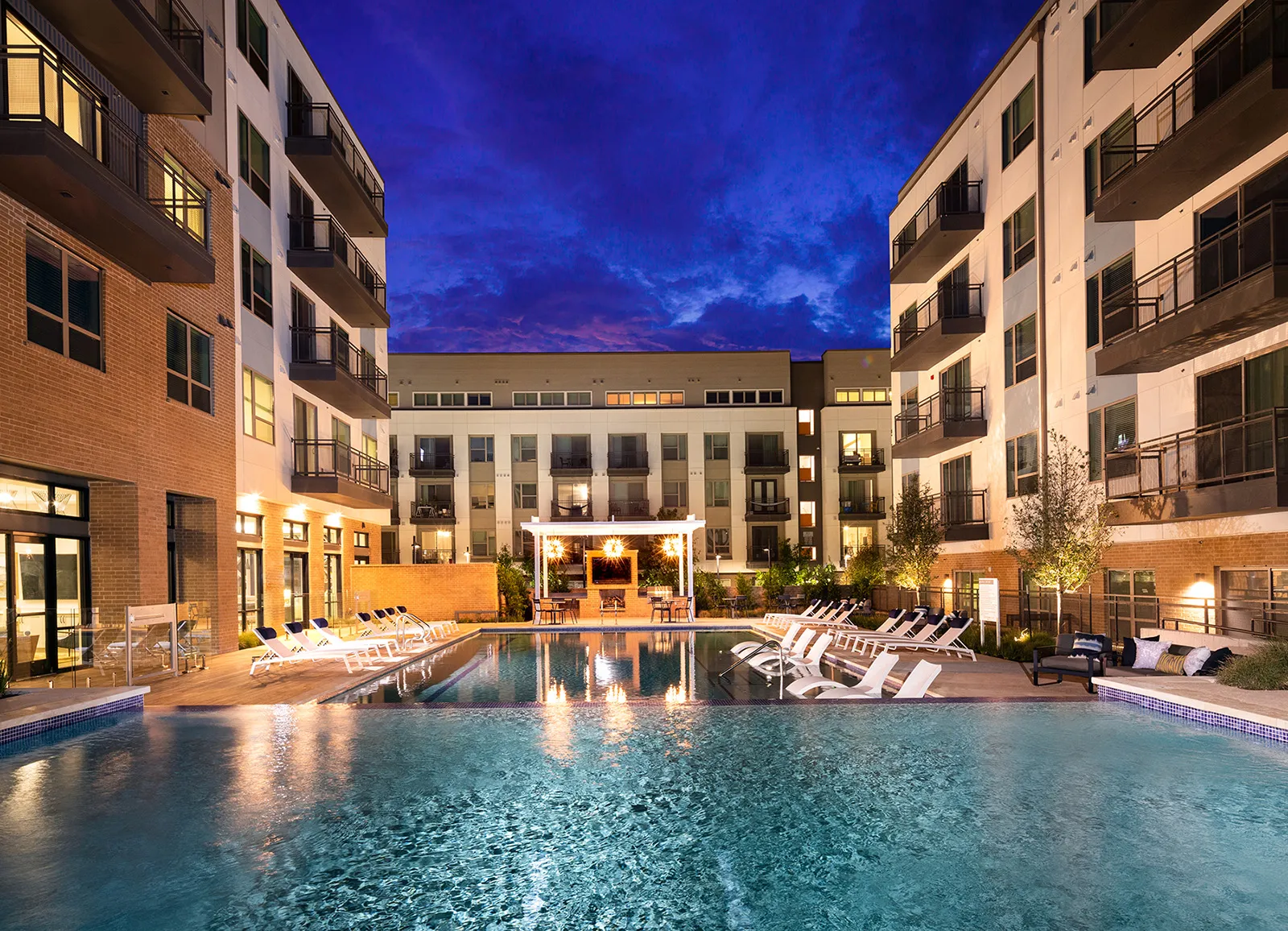 Infinity pool and interior courtyard in the evening with apartments overlooking and a deep blue sky at AVE Austin Community